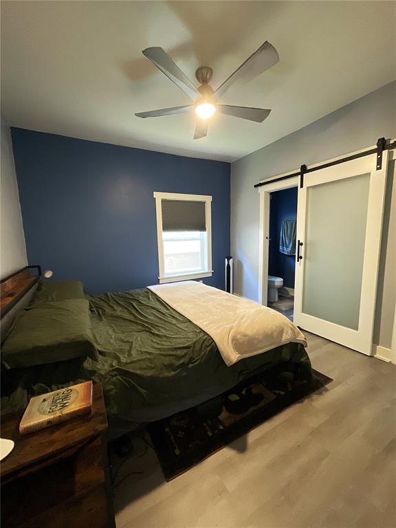 1509 Booker St, Hannibal, MO 63401 - bedroom featuring a barn door, wood finished floors, ceiling fan, ensuite bath, and baseboards