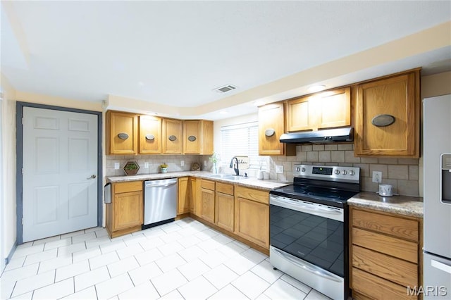 11230 W Little Oaks Rd, Rolla, MO 65401 - kitchen with appliances with stainless steel finishes, under cabinet range hood, a sink, backsplash, and light countertops