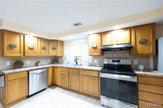 11230 W Little Oaks Rd, Rolla, MO 65401 - kitchen with appliances with stainless steel finishes, under cabinet range hood, a sink, backsplash, and brown cabinetry