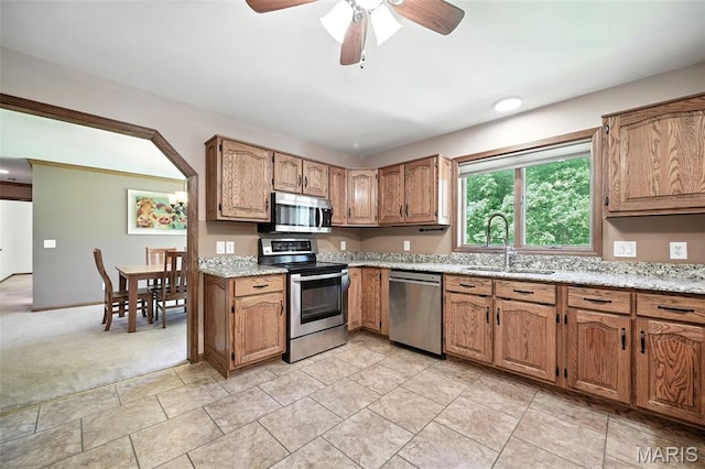 20731 Columbine Dr, Warrenton, MO 63383 - kitchen featuring stainless steel appliances, a ceiling fan, brown cabinets, light colored carpet, and light stone counters
