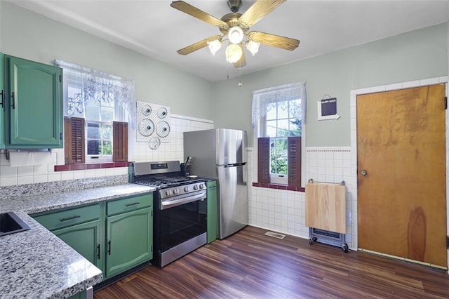 4444 Taft Ave, Saint Louis, MO 63116 - kitchen with stainless steel appliances, green cabinetry, a ceiling fan, dark wood finished floors, and tile walls