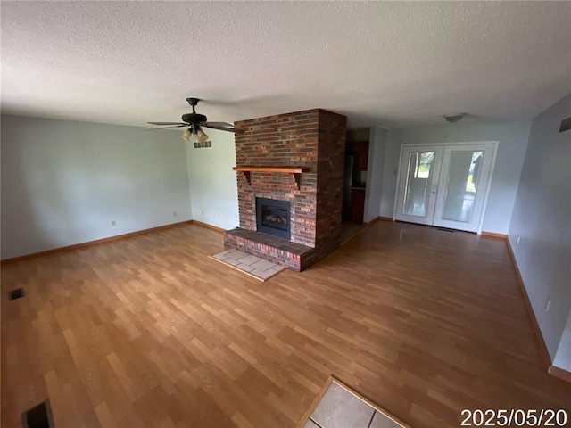 404 Glen Echo Dr, De Soto, MO 63020 - unfurnished living room with a textured ceiling, wood finished floors, a ceiling fan, baseboards, and a brick fireplace