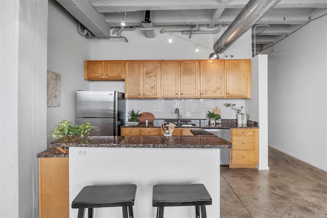 1720 Chouteau Ave Unit 303, Saint Louis, MO 63103 - kitchen featuring stainless steel appliances, a sink, decorative backsplash, finished concrete flooring, and dark stone countertops