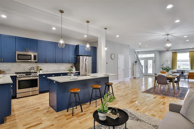 4412 Chouteau, Saint Louis, MO 63110 - kitchen with blue cabinetry, stainless steel appliances, light countertops, a breakfast bar area, and backsplash