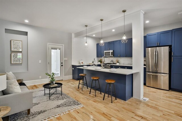 4412 Chouteau, Saint Louis, MO 63110 - kitchen with appliances with stainless steel finishes, blue cabinetry, a kitchen bar, light countertops, and decorative backsplash