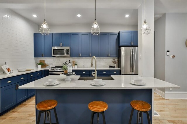 4412 Chouteau, Saint Louis, MO 63110 - kitchen featuring appliances with stainless steel finishes, blue cabinets, a sink, a breakfast bar area, and light wood-type flooring