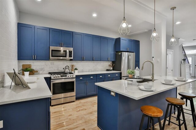 4412 Chouteau, Saint Louis, MO 63110 - kitchen with appliances with stainless steel finishes, blue cabinetry, a sink, a breakfast bar, and decorative backsplash