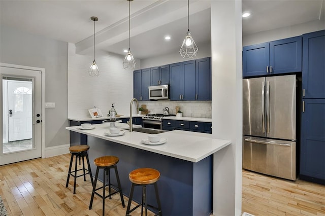 4412 Chouteau, Saint Louis, MO 63110 - kitchen featuring appliances with stainless steel finishes, blue cabinetry, a sink, a kitchen bar, and recessed lighting