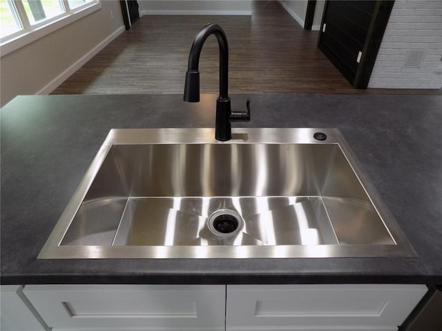 633 E Eldon St, St James, MO 65559 - kitchen view of a sink, white cabinetry, dark countertops, and baseboards