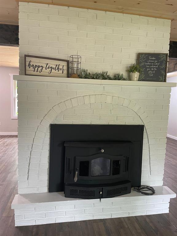 633 E Eldon St, St James, MO 65559 - detailed view of wood finished floors, a wood stove, and baseboards