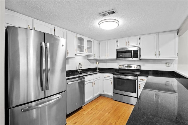 537 Colebrook Dr Unit C, Webster Groves, MO 63119 - kitchen with stainless steel appliances, a sink, white cabinets, a textured ceiling, and dark stone counters