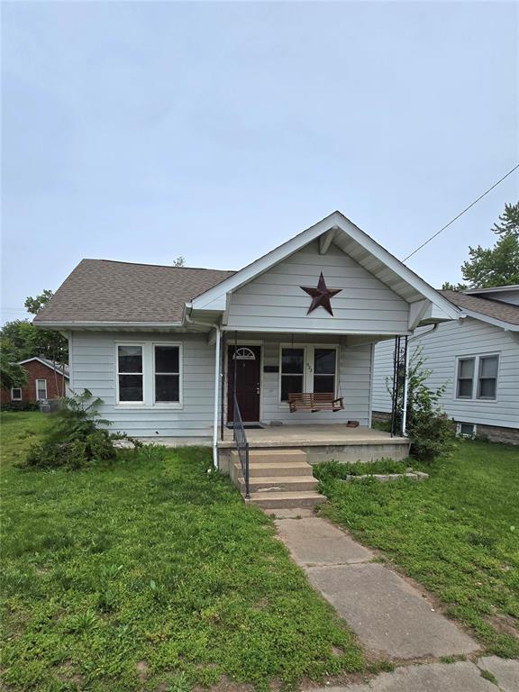 523 E Acton Ave, Wood River, IL 62095 - bungalow featuring a front yard, a porch, and a shingled roof