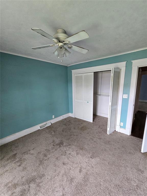 523 E Acton Ave, Wood River, IL 62095 - unfurnished bedroom featuring carpet floors, a closet, baseboards, ornamental molding, and a ceiling fan