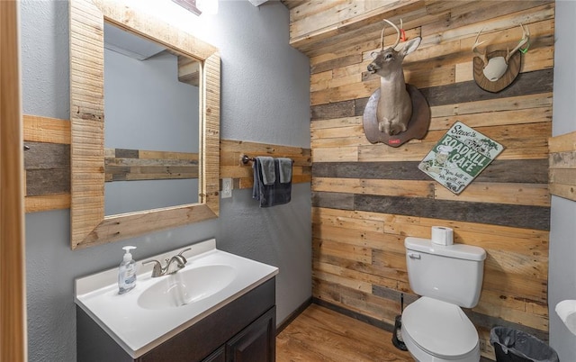 19285 State Route Ee, St James, MO 65559 - half bathroom with toilet, wooden walls, vanity, wood finished floors, and a textured wall