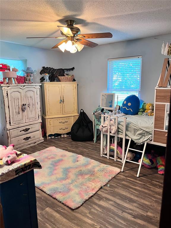 12241 Pipeline Rd, Bourbon, MO 65441 - bedroom with dark wood-style floors, a textured ceiling, and a ceiling fan