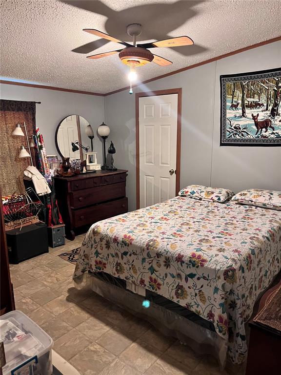 12241 Pipeline Rd, Bourbon, MO 65441 - bedroom featuring crown molding, a textured ceiling, and a ceiling fan