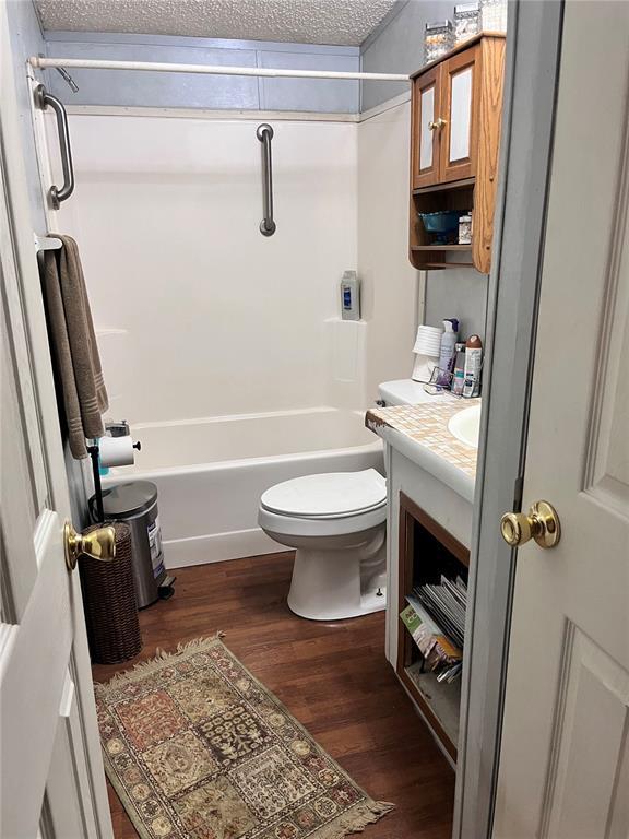 12241 Pipeline Rd, Bourbon, MO 65441 - bathroom with vanity, wood finished floors, toilet,  shower combination, and a textured ceiling