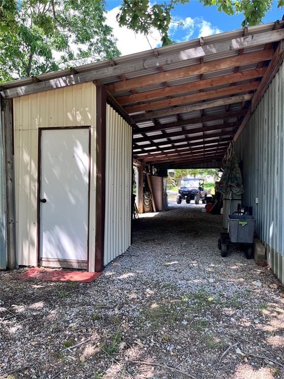 12241 Pipeline Rd, Bourbon, MO 65441 - garage with an attached carport, gravel driveway, and a storage unit