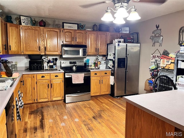 12241 Pipeline Rd, Bourbon, MO 65441 - kitchen featuring stainless steel appliances, light countertops, light wood finished floors, and brown cabinets