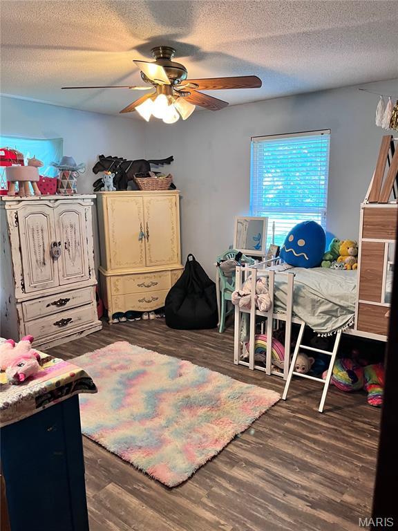 12241 Pipeline Rd, Bourbon, MO 65441 - bedroom with dark wood-type flooring, a textured ceiling, and a ceiling fan