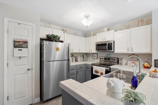 321 Kipling Way Unit G, Weldon Spring, MO 63304 - kitchen featuring appliances with stainless steel finishes, tile counters, gray cabinetry, a sink, and white cabinetry