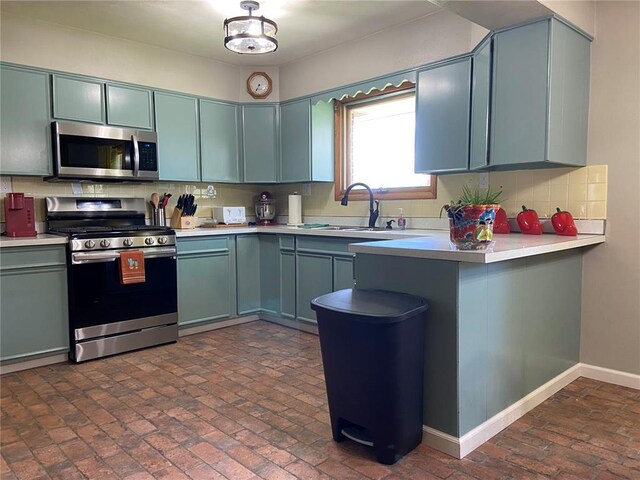 1018 S Spring St, Palmyra, MO 63461 - kitchen featuring appliances with stainless steel finishes, a sink, light countertops, and brick flooring