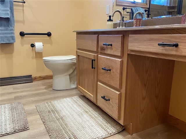 1018 S Spring St, Palmyra, MO 63461 - bathroom with vanity, a baseboard heating unit, wood finished floors, and toilet