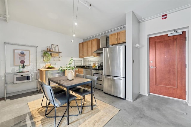 1720 Chouteau Ave Unit 110, Saint Louis, MO 63103 - kitchen featuring appliances with stainless steel finishes, concrete floors, dark countertops, wall chimney range hood, and a sink