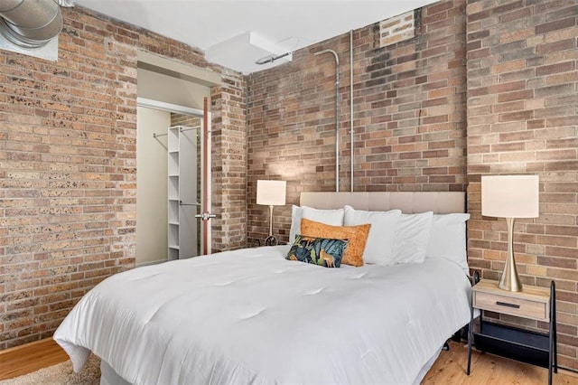 1720 Chouteau Ave Unit 110, Saint Louis, MO 63103 - bedroom with brick wall and wood finished floors