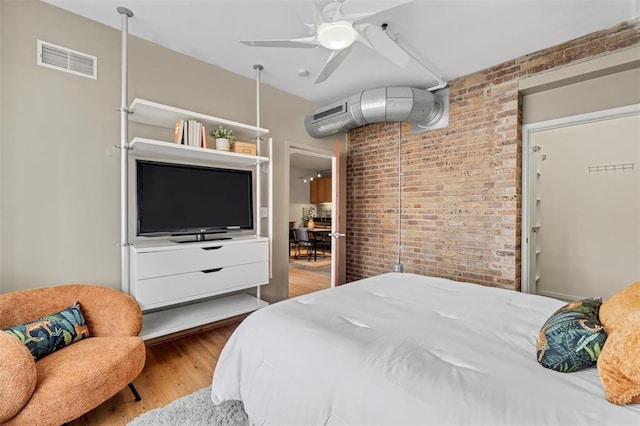 1720 Chouteau Ave Unit 110, Saint Louis, MO 63103 - bedroom with brick wall, wood finished floors, and ceiling fan