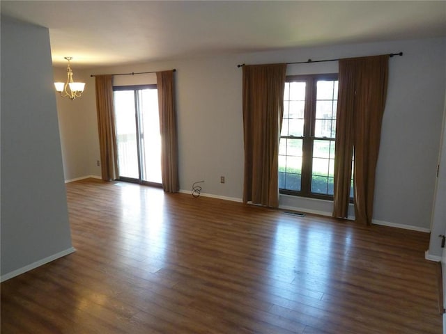 1133 Appleseed Ln Unit B, Saint Louis, MO 63132 - empty room with healthy amount of natural light, a chandelier, wood finished floors, and baseboards