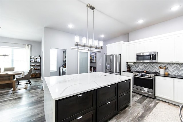 11475 Slate Cir, Rolla, MO 65401 - kitchen with appliances with stainless steel finishes, dark cabinetry, backsplash, a barn door, and dark wood finished floors