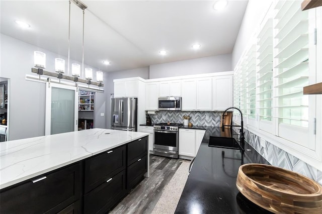 11475 Slate Cir, Rolla, MO 65401 - kitchen with appliances with stainless steel finishes, a sink, dark cabinetry, a barn door, and white cabinets