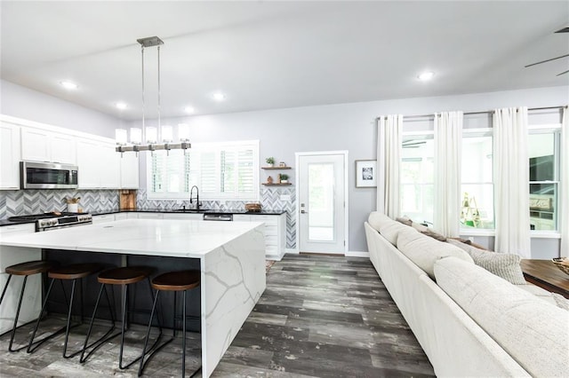 11475 Slate Cir, Rolla, MO 65401 - kitchen with appliances with stainless steel finishes, open floor plan, a kitchen island, backsplash, and a kitchen bar