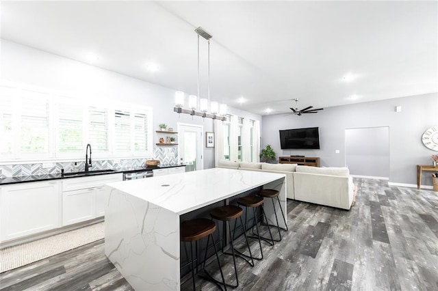 11475 Slate Cir, Rolla, MO 65401 - kitchen featuring a sink, wood finished floors, a center island, a ceiling fan, and dark stone countertops