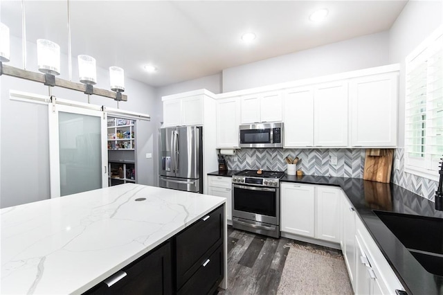 11475 Slate Cir, Rolla, MO 65401 - kitchen featuring stainless steel appliances, dark wood-style floors, tasteful backsplash, a barn door, and white cabinetry