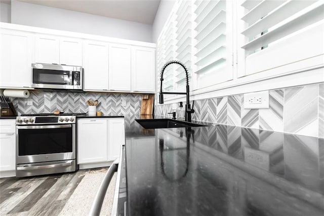 11475 Slate Cir, Rolla, MO 65401 - kitchen with appliances with stainless steel finishes, dark countertops, decorative backsplash, and wood finished floors
