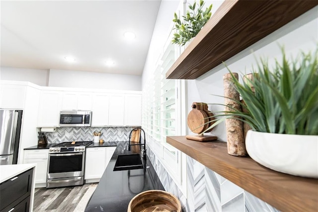 11475 Slate Cir, Rolla, MO 65401 - kitchen with stainless steel appliances, a sink, white cabinetry, tasteful backsplash, and wood finished floors