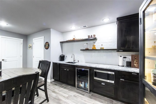 11475 Slate Cir, Rolla, MO 65401 - indoor wet bar with beverage cooler, stainless steel microwave, tasteful backsplash, light wood finished floors, and baseboards