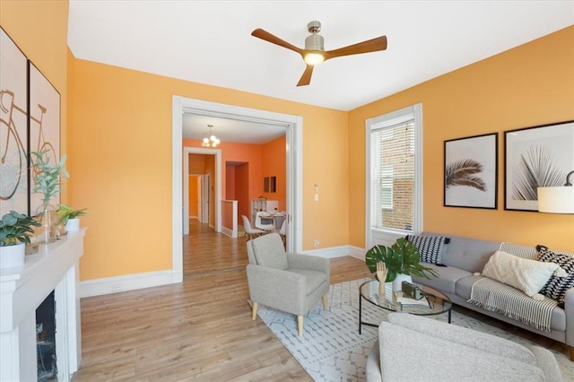4366 Swan Ave, Saint Louis, MO 63110 - living room featuring light wood-style floors, ceiling fan, baseboards, and a chandelier