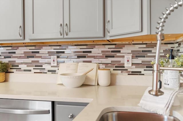 4366 Swan Ave, Saint Louis, MO 63110 - kitchen view of decorative backsplash, stainless steel dishwasher, gray cabinetry, and light stone counters