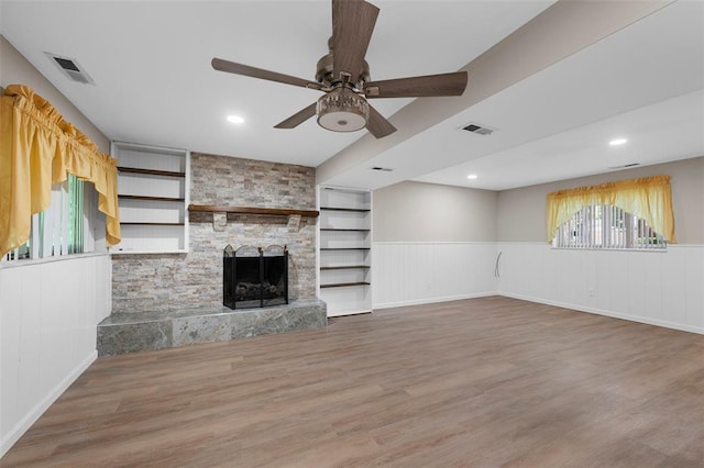 5 Braquewood Ct, Manchester, MO 63021 - unfurnished living room featuring a ceiling fan, a wainscoted wall, plenty of natural light, wood finished floors, and a stone fireplace