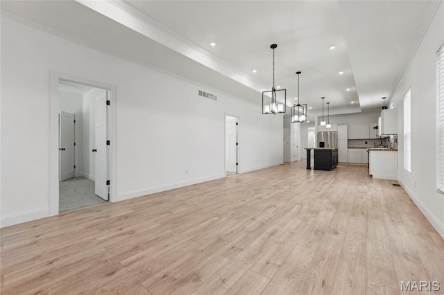125 Foxwoods Ct, Troy, MO 63379 - unfurnished living room featuring a tray ceiling, a chandelier, light wood-style flooring, recessed lighting, and ornamental molding