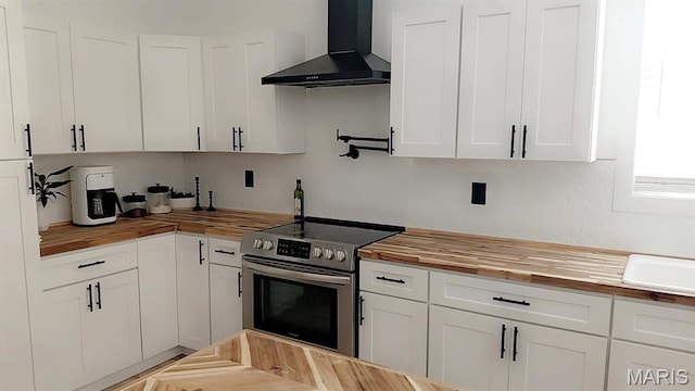 125 Foxwoods Ct, Troy, MO 63379 - kitchen featuring butcher block countertops, wall chimney range hood, stainless steel range with electric cooktop, and white cabinets