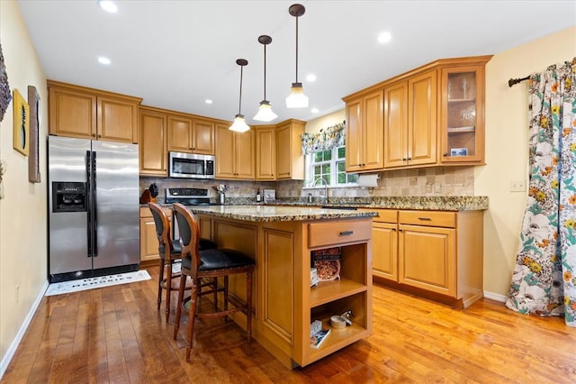 3226 Bridgeport Place Dr, Bridgeton, MO 63044 - kitchen with stainless steel appliances, light wood-style floors, decorative backsplash, a center island, and a kitchen bar