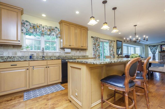3226 Bridgeport Place Dr, Bridgeton, MO 63044 - kitchen with black dishwasher, a chandelier, light stone counters, backsplash, and light wood-style flooring