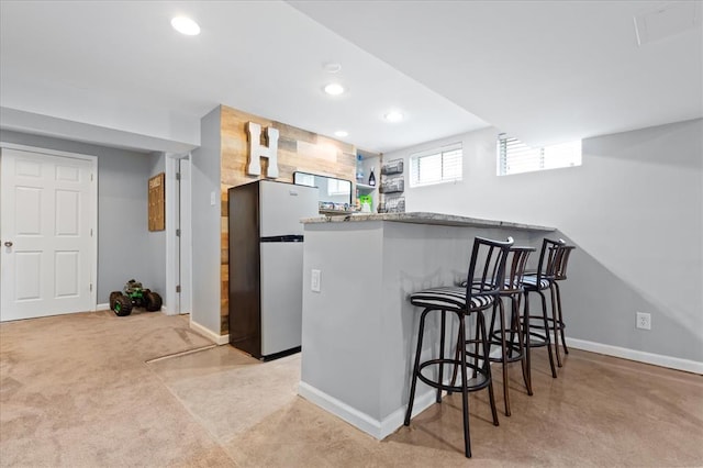 3226 Bridgeport Place Dr, Bridgeton, MO 63044 - kitchen with freestanding refrigerator, recessed lighting, a breakfast bar, a peninsula, and baseboards