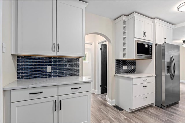 426 Pasadena Ave, Webster Groves, MO 63119 - kitchen with appliances with stainless steel finishes, open shelves, arched walkways, white cabinetry, and light wood finished floors