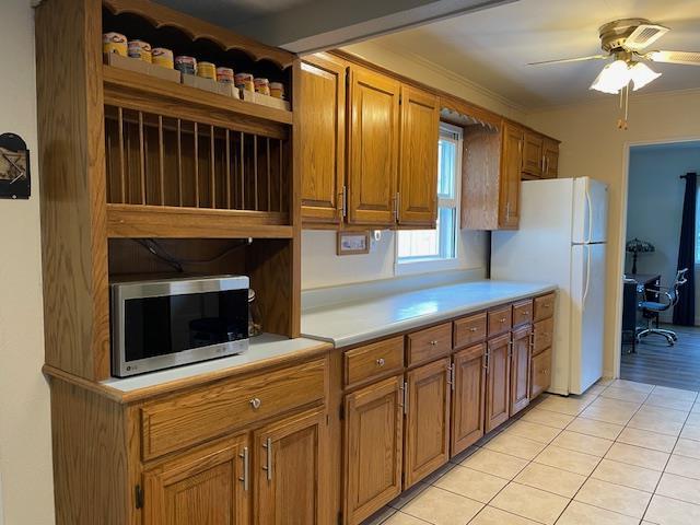 212 E N St, Benton, MO 63736 - kitchen with stainless steel microwave, open shelves, freestanding refrigerator, light countertops, and light tile patterned floors
