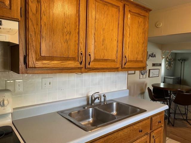 212 E N St, Benton, MO 63736 - kitchen featuring brown cabinetry, a sink, backsplash, and light countertops
